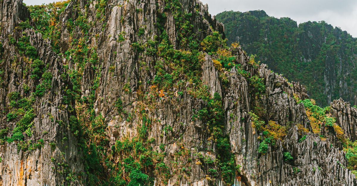 Traditional bangka boats beside limestone cliffs near El Nido's Small Lagoon