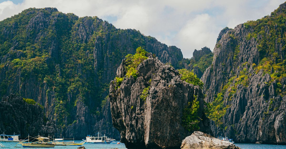 Boats anchored near Big Lagoon limestone cliffs El Nido Palawan Philippines