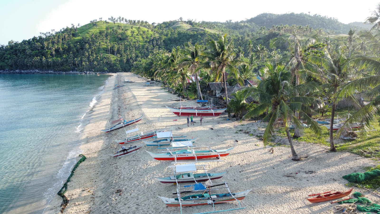 White sand beach with bangka boats lined up along the shore in Palawan near Port Barton