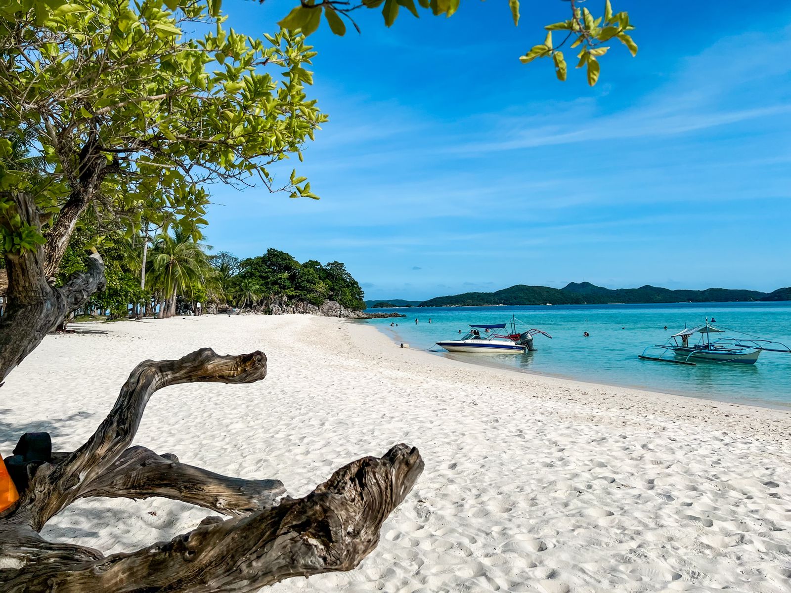 Boats along a Palawan beach, a common island hopping scene paired with a Maquinit Hot Springs visit