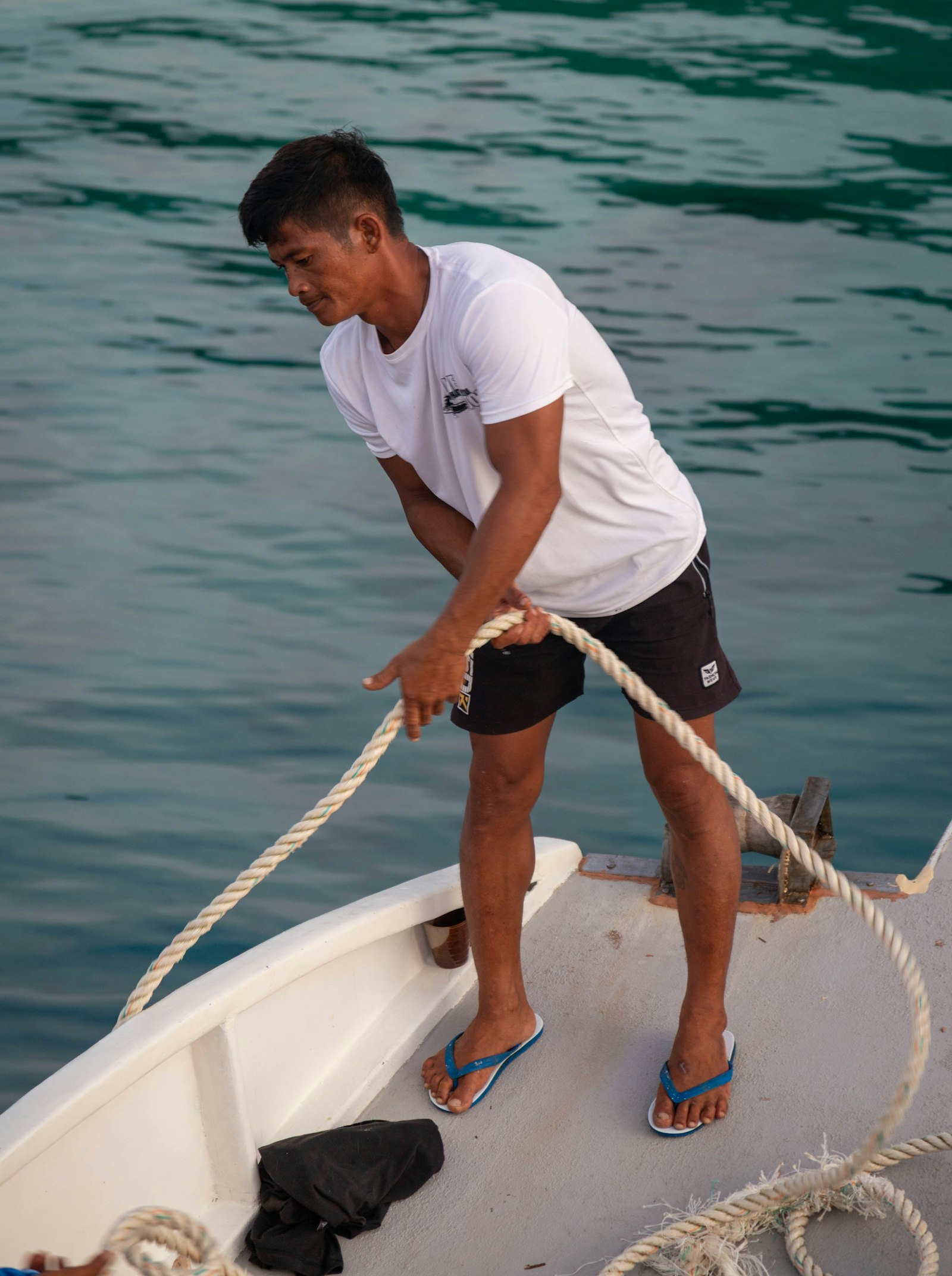 Boatman handling rope on a Philippine outrigger, typical of Port Barton boat arrivals