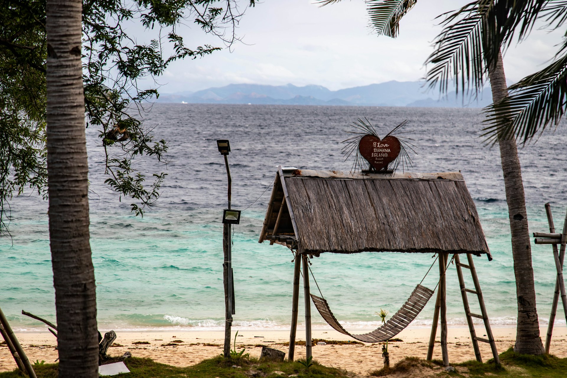 Hammock strung between palm trees on a quiet Palawan beach, the pace of a Port Barton stay