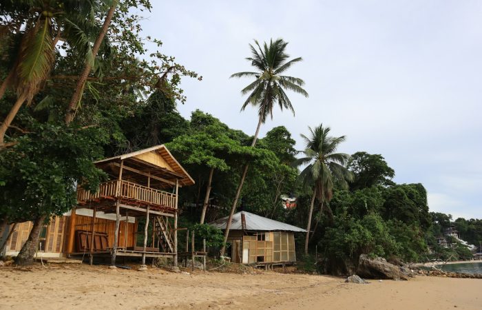 Beachfront wooden bungalows and palm trees in El Nido, a typical mid-range El Nido budget per day stay