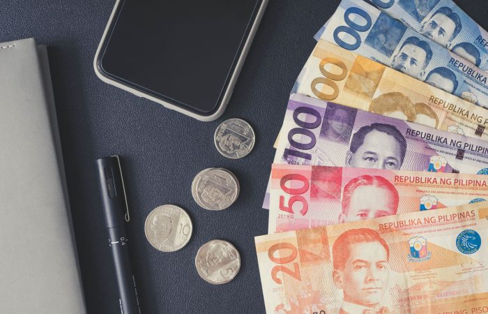 Philippine peso bills, coins and a smartphone laid out for planning money in Palawan