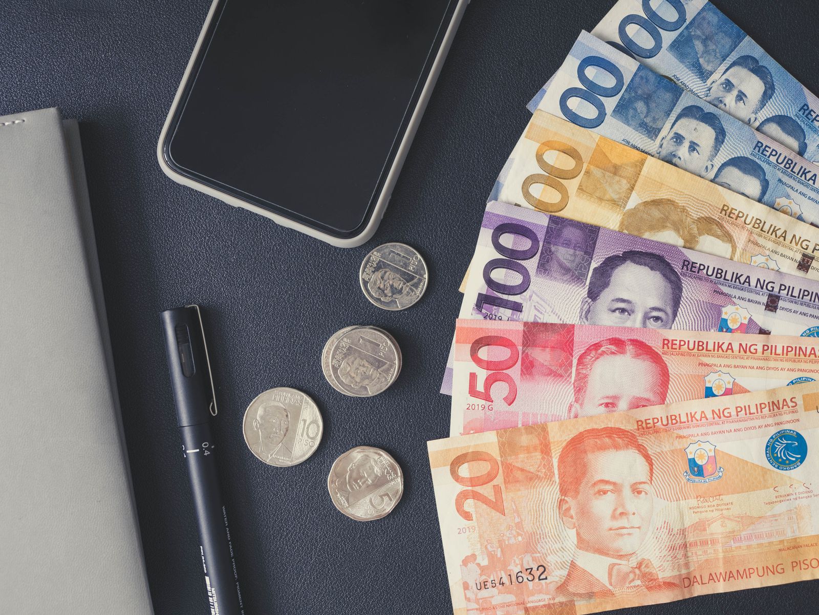 Philippine peso bills, coins and a smartphone laid out for planning money in Palawan