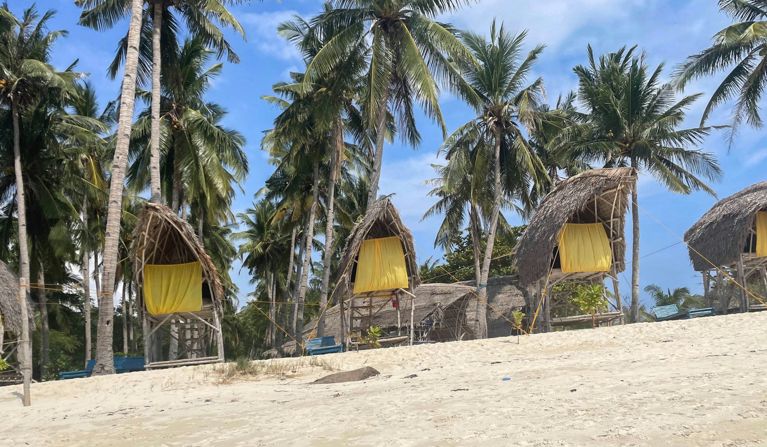 Simple thatched beach huts on the sand in Palawan, the style of cheap room Port Barton budget travel is built on