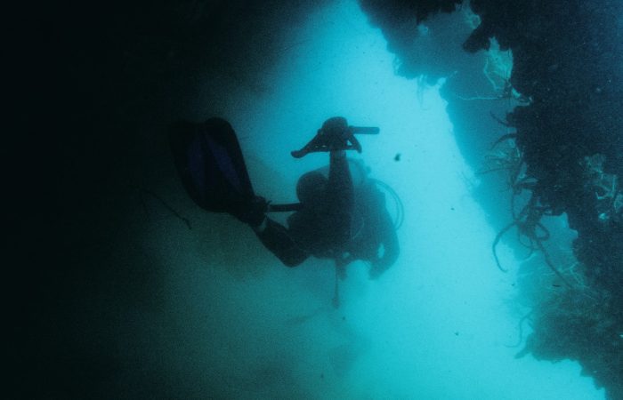 Scuba diver exploring a dark underwater WW2 shipwreck in the Philippines, similar to Coron Bay's wrecks