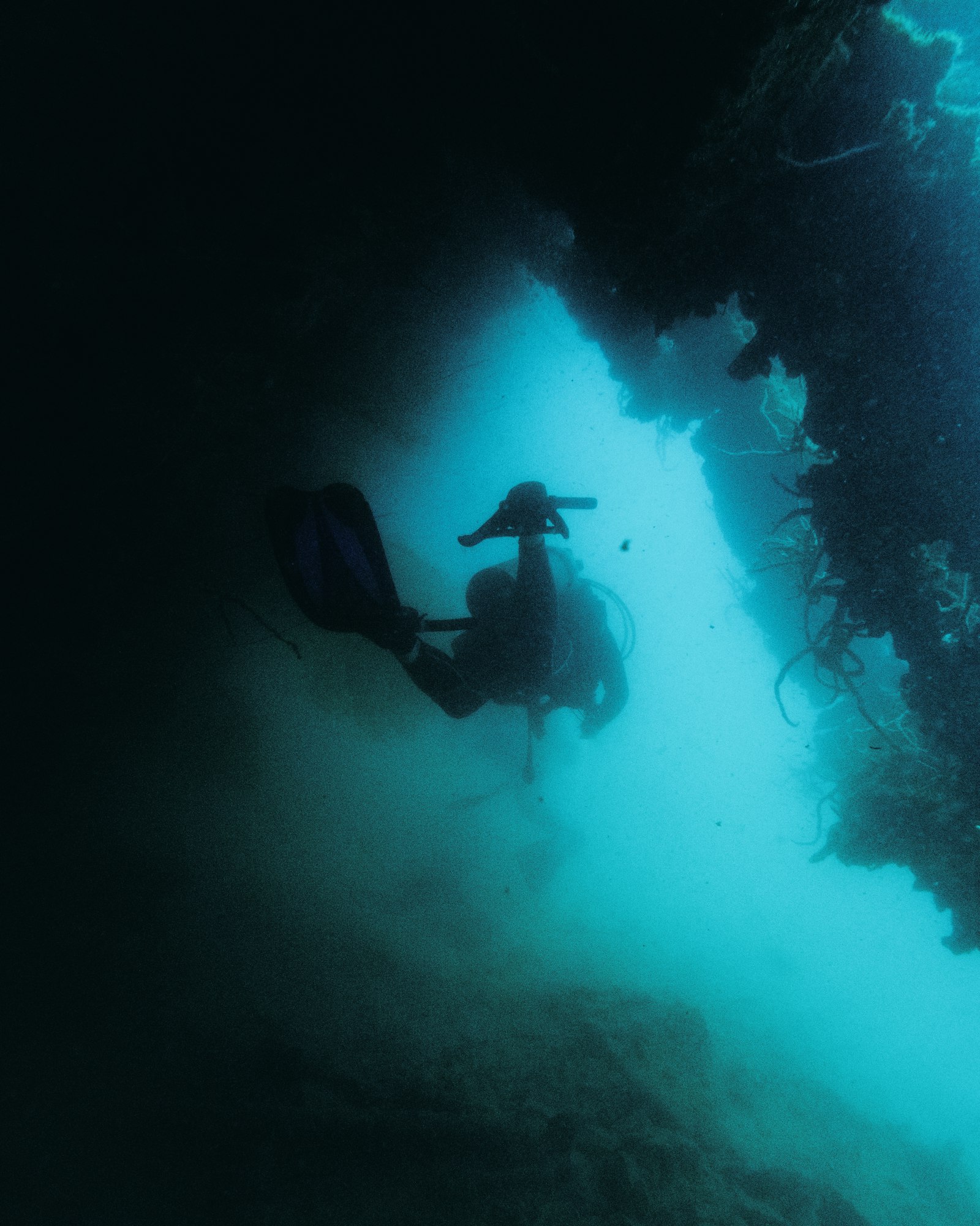 Scuba diver exploring a dark underwater WW2 shipwreck in the Philippines, similar to Coron Bay's wrecks